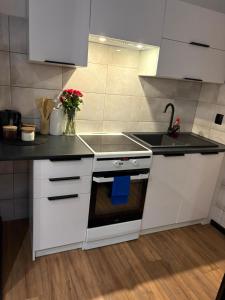 a kitchen with white cabinets and a stove and a sink at Zakątek Centrum 3 in Suwałki
