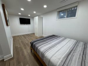 ein Schlafzimmer mit einem Bett und einem Flachbildfernseher in der Unterkunft North Barrie !A Stylish and Spacious Private Bedroom with Private Bathroom in Barrie