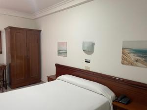 een slaapkamer met twee bedden en een tv aan de muur bij Avenida Gijón Centro in Gijón