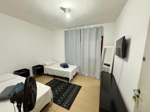 a room with two beds and a flat screen tv at Quartos Vila Olímpia 1 in Sao Paulo