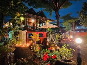 a house with a statue in a garden at night at Thai Tom s GuestHouse in Chiang Mai