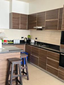 a kitchen with wooden cabinets and two stools at The Happy Nest in Kampala