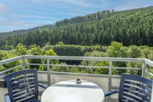 a table and chairs on a balcony with a view of trees at Waldhaus am See in Willingen