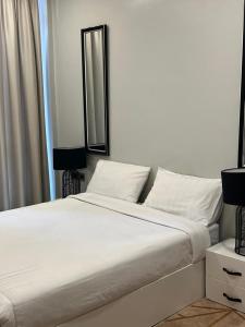 a white bed with white pillows and a mirror at The Happy Nest in Kampala