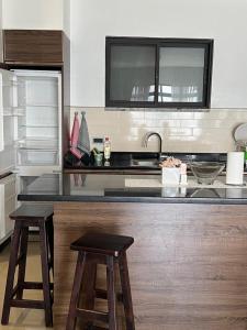 a kitchen with a counter with two stools and a sink at The Happy Nest in Kampala +5 photos