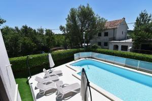 a swimming pool with lounge chairs next to a house at Villa Maravilla in Jadranovo