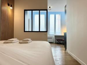 a bedroom with a bed with two towels on it at Wellness Suite Ponsardin RDC - Reims Centre in Reims