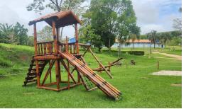 a wooden play structure in a field of grass at Quinta das Águas Hotel in Itapira