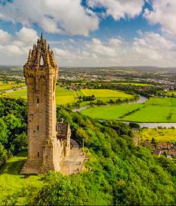 an old tower on top of a green hill at Cosy Hideaway in Stirling