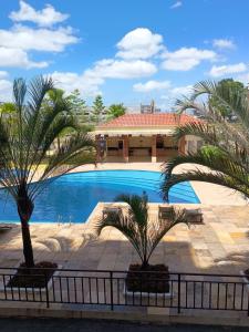 a swimming pool with two palm trees in front of a building at COP 30 aconchego e conforto in Ananindeua