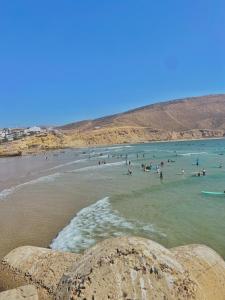 a group of people in the water at a beach at Tayoukhte Surf Camp Imsouane in Imsouane