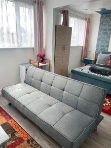 ein graues Sofa in einem Zimmer mit einem Schlafzimmer in der Unterkunft 12 Penn Gardens- Apart 2 in Friern Barnet