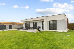 une maison blanche avec une cour verdoyante dans l'établissement Klimatizovaný Apartmánový dom s vírivkou, 9B, à Jánošíková