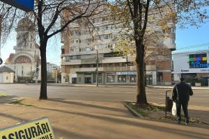 a man walking down a city street with a building at Eve's Central in Brăila