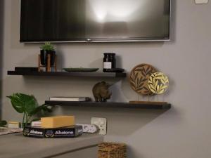 a television hanging on a wall with shelves at The Lantern Guesthouse in Bloemfontein