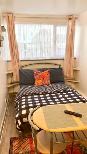 Bett in einem Zimmer mit einem Tisch und einem Fenster in der Unterkunft 12 Penn Gardens- Apart 2 in Friern Barnet
