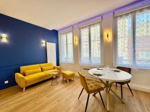 a living room with a yellow couch and a table at Wellness Suite Ponsardin 1 - Reims Centre in Reims
