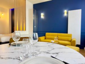 a table with wine glasses on it with a yellow couch at Wellness Suite Ponsardin 1 - Reims Centre in Reims