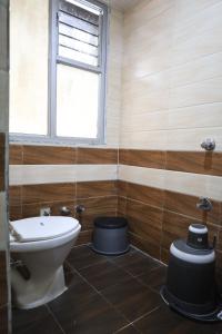 a bathroom with a toilet and a window at Hotel Aasopalav in Ahmedabad
