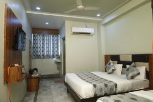 a hotel room with two beds and a bathroom at Hotel Aasopalav in Ahmedabad