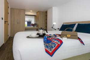 ein weißes Bett mit einer Tasche und einem Tablett darauf in der Unterkunft Pool Access 1 Bedroom Duplex UTL A107 near Nai Harn Beach in Rawai Beach + 14 Fotos