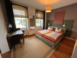 een slaapkamer met een bed, een bureau en ramen bij Brandt Apartments in Erfurt