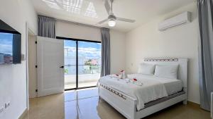 a white bedroom with a bed and a large window at Sosua Ocean Village - Villas Marinas 27B in Sosúa