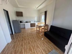 een woonkamer met een zwarte bank en een keuken bij Wimanthara houses in Thongsala