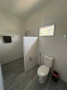 een badkamer met een wit toilet en een raam bij Wimanthara houses in Thongsala