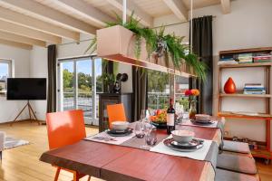 a dining room with a wooden table and orange chairs at Svyvo Cologne-Esch Design Apartment in Cologne
