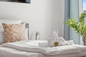 a white bed with a stuffed animal on it at Svyvo Cologne-Esch Design Apartment in Cologne
