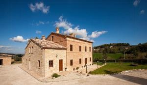 un vieux bâtiment en briques avec une cour herbeuse devant dans l'établissement Historic Villa With Pool In Marche Hills, à SantʼAngelo in Pontano