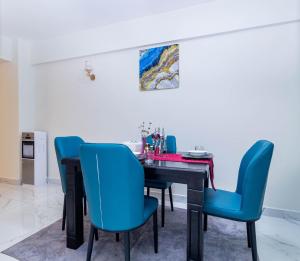 a dining room with a table and blue chairs at Luxurious Nairobi Apartment with City and Garden Views in Nairobi