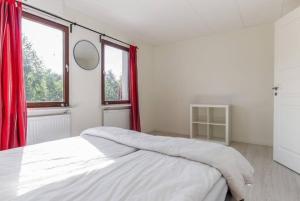 a white bedroom with a large bed with red curtains at Day To Day Motel in Ludvika