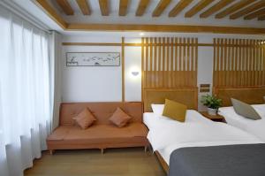 Una habitación con dos camas y un sofá. en Lijiang Tongfu Inn, en Lijiang