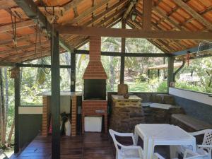 Una chimenea en un pabellón con una mesa y sillas. en Sítio Toca da Onça- Lumiar, en Nova Friburgo