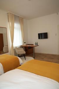 um quarto de hotel com duas camas e uma escrivaninha em Hotel Mutter Buermann em Hemmingen