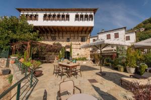 Un patio con mesa y sillas y un edificio. en Αρχοντικό 1716, en Agios Lavredios