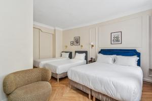 ein Hotelzimmer mit zwei Betten und einem Stuhl in der Unterkunft Hotel Le Clery in Paris