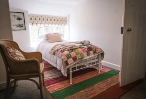 Apsley Cottage في Trotton: غرفة نوم بها سرير وكرسي ونافذة