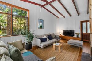 a living room with a couch and a tv at Forest Trails Escape - Bushland Serenity near Beach in Austinmer