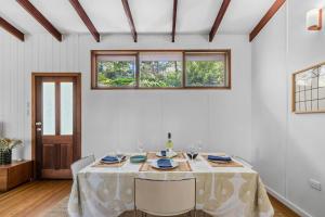 a white dining room with a table and chairs at Forest Trails Escape - Bushland Serenity near Beach in Austinmer