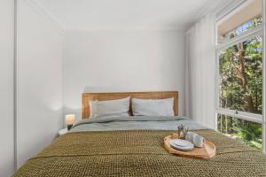 a bedroom with a bed with a tray of food on it at Forest Trails Escape - Bushland Serenity near Beach in Austinmer