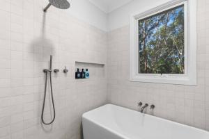 a white bathroom with a shower and a tub at Forest Trails Escape - Bushland Serenity near Beach in Austinmer +26 photos