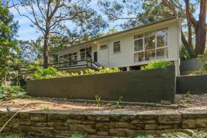a house with a stone wall in front of it at Forest Trails Escape - Bushland Serenity near Beach in Austinmer
