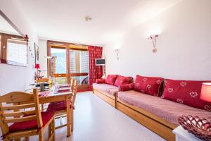 a living room with a red couch and a table at Notre Petite Famille - Station Le Corbier in Villarembert