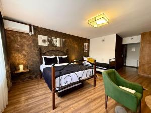a bedroom with a bed and a green chair at Hotel Fjor in Prizren +5 photos