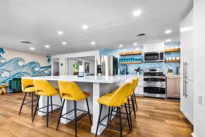 eine Küche mit gelben Stühlen und einer weißen Arbeitsplatte in der Unterkunft 6br Sleeps 21 Tropical Villa Heated Pool Hot Tub in Cedar Hammock