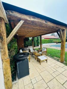 a wooden patio with a grill and tables and chairs at L escapade de l'Ancien Rail in Pouilly-sous-Charlieu