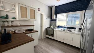 eine Küche mit weißen Schränken und einem Edelstahlkühlschrank in der Unterkunft Refúgio em Juquehy no centro a poucos metros do mar com piscina privativa aquecida in São Sebastião